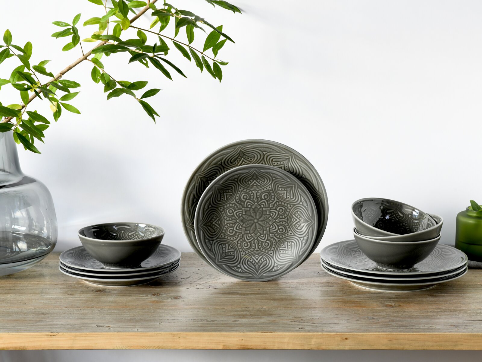 Creatable Tellerset 12-tlg ORIENT MANDALA Graues Keramik-Geschirrset mit Mandala-Prägung (Teller und Schalen) auf Holztisch vor weißem Hintergrund, frontale Perspektive auf Augenhöhe