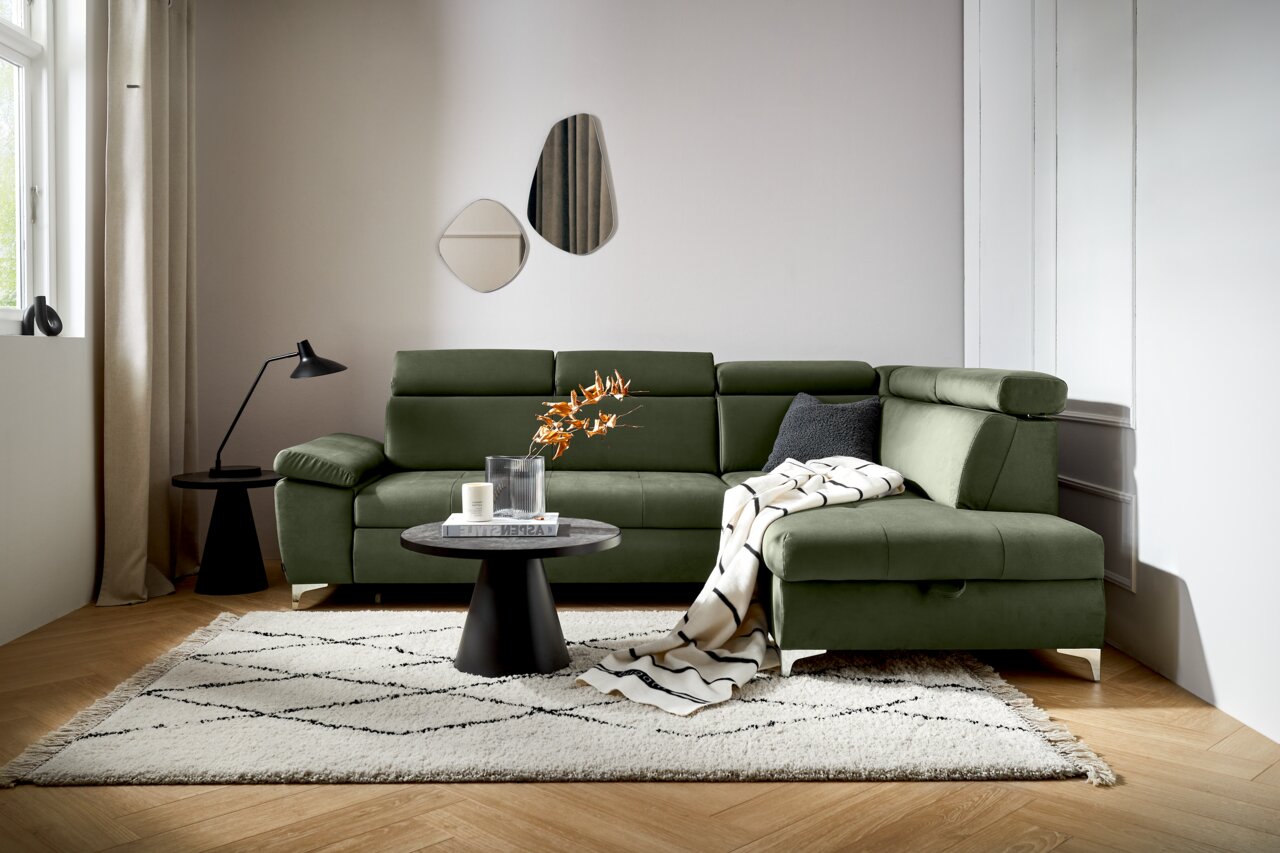 Groene hoekbank in een moderne woonkamer, gezien vanaf de voorkant, met een bijzettafeltje en decoraties.