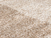 Nahaufnahme eines weichen, beigen Teppichs mit flauschiger Textur, perspektivisch von der Seite aufgenommen.