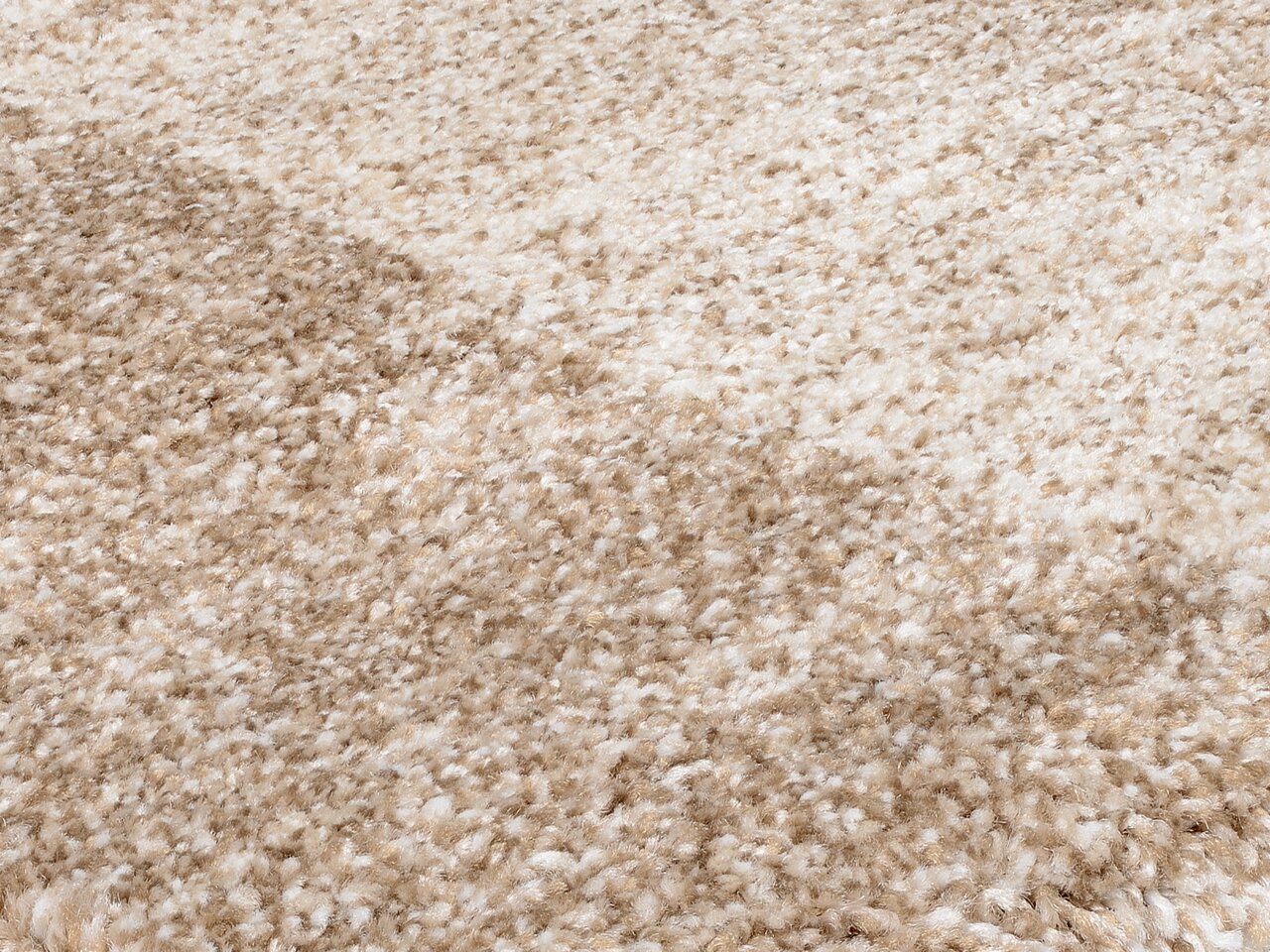 Nahaufnahme eines weichen, beigen Teppichs mit flauschiger Textur, perspektivisch von der Seite aufgenommen.