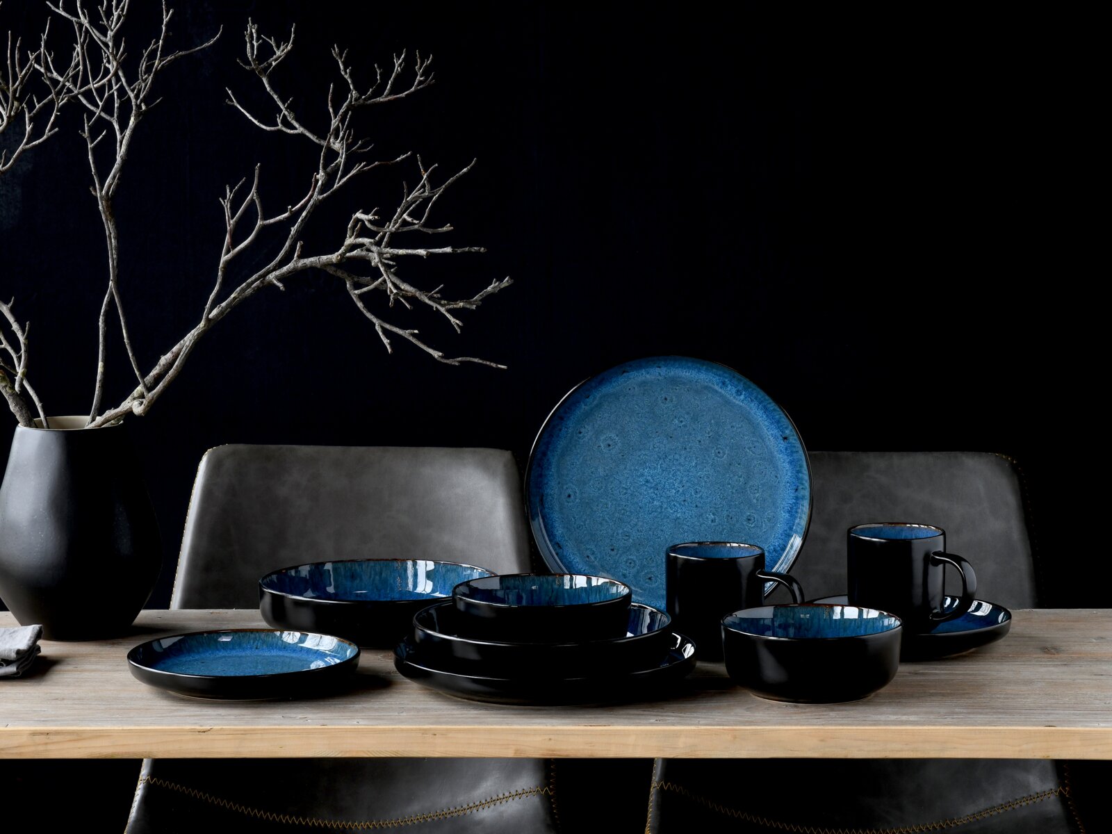 Kombiservice 16-tlg in elegantem Schwarz und Blau, bestehend aus Tellern, Schalen und Tassen, auf einem Tisch arrangiert, seitliche Perspektive.