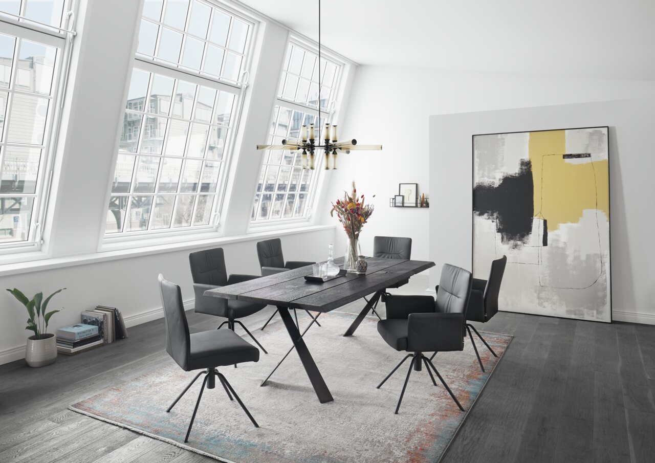 Moderner Essbereich mit sechs schwarzen Sesseln um einen dunklen Holztisch, seitliche Perspektive.