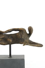 Bronzefarbene Skulptur eines liegenden abstrakten Menschen auf einem Sockel, seitliche Perspektive