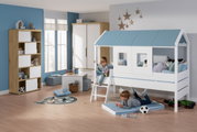 Kinderkamer met een hoogslaper in de vorm van een huisje met blauwe dakspanen, twee spelende kinderen, één op de ladder en één op een mat eronder, gezien van voren.