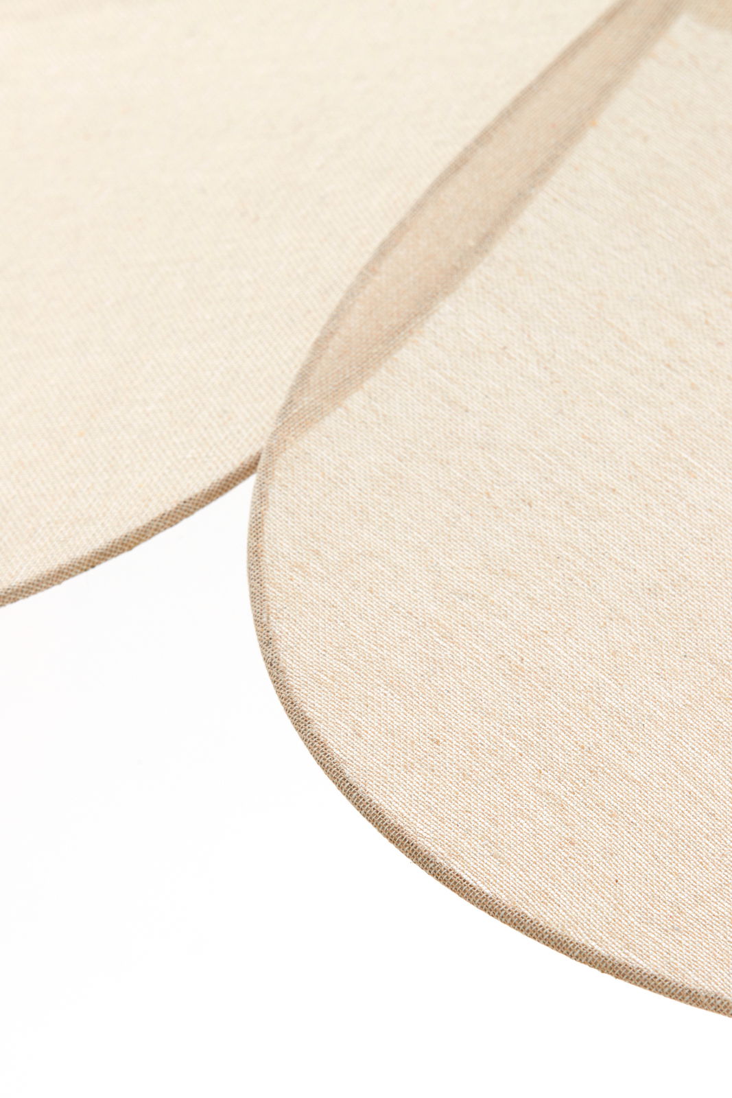 Nahaufnahme der Textur einer Hängeleuchte mit beigem Stoff, perspektivisch von oben betrachtet.