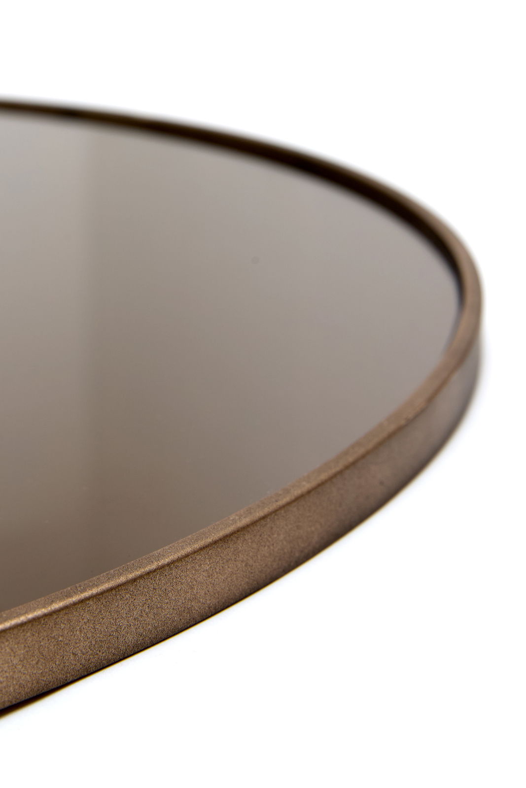 Nahaufnahme eines runden Spiegels mit einem schmalen, bronzefarbenen Rahmen, seitliche Perspektive