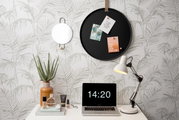Rundes schwarzes Memoboard an der Wand mit drei befestigten Karten, umgeben von einem dekorativen Spiegel, einer Tischlampe und einem Laptop auf einem Schreibtisch. Perspektive: Frontalansicht.