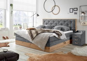 Gemütliches Schlafzimmer mit Boxspringbett und Nachtkonsole in moderner Einrichtung, seitliche Perspektive