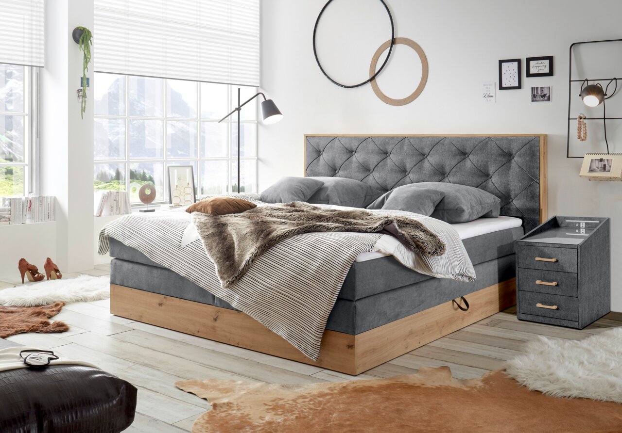 Gemütliches Schlafzimmer mit Boxspringbett und Nachtkonsole in moderner Einrichtung, seitliche Perspektive
