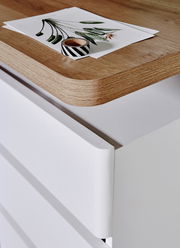 Nahaufnahme eines Schreibtisches mit einer Holzoberfläche und weißen Schubladen, von oben betrachtet.