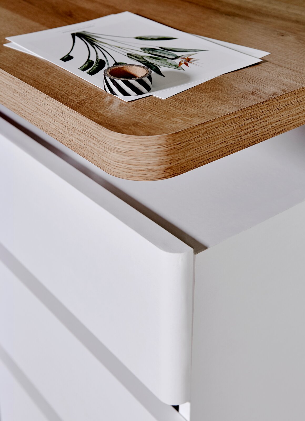 Nahaufnahme eines Schreibtisches mit einer Holzoberfläche und weißen Schubladen, von oben betrachtet.