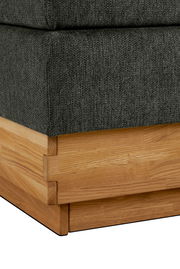 Nahaufnahme eines Boxspringbettes mit grauem Stoffbezug und Holzrahmen, Perspektive von der Ecke.