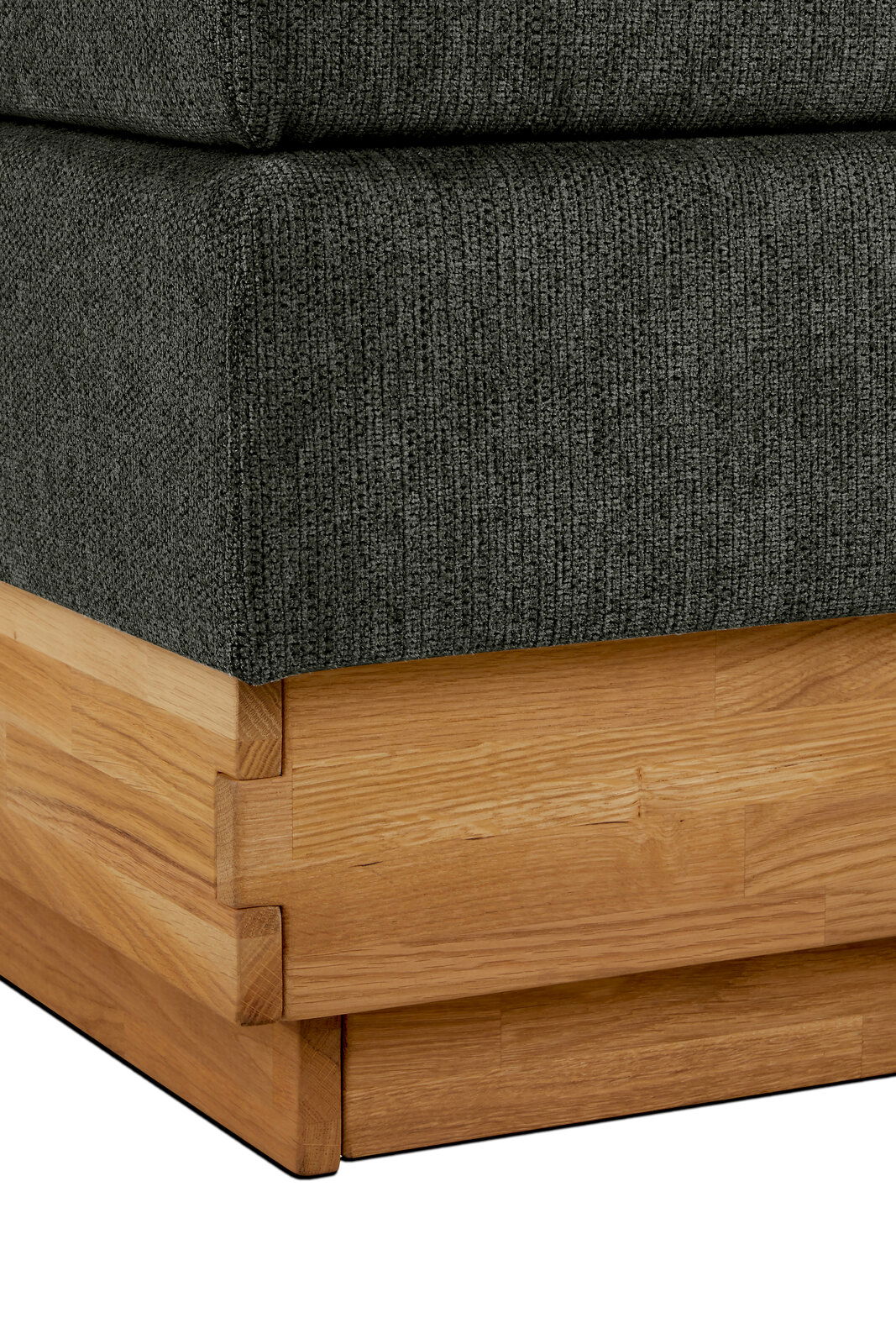 Nahaufnahme eines Boxspringbettes mit grauem Stoffbezug und Holzrahmen, Perspektive von der Ecke.