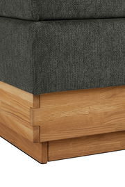 Nahaufnahme eines Boxspringbettes mit grauem Stoffbezug und Holzrahmen, Perspektive von der Ecke.