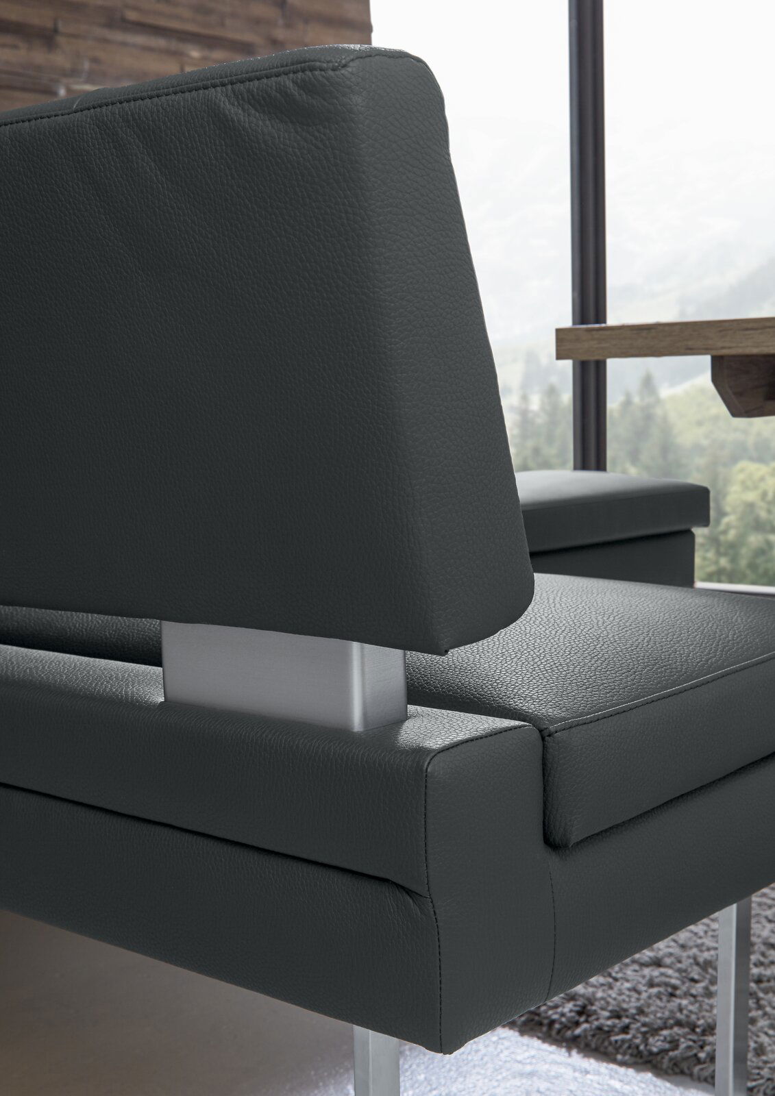 Nahaufnahme einer modernen Eckbank mit dunkelgrauem Lederbezug und Metallgestell, seitliche Perspektive.