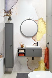 Modernes Waschtisch-Set in einem stilvollen Badezimmer mit grauen Schränken, rundem Spiegel und dekorativen Elementen, aus der Perspektive von vorne betrachtet.