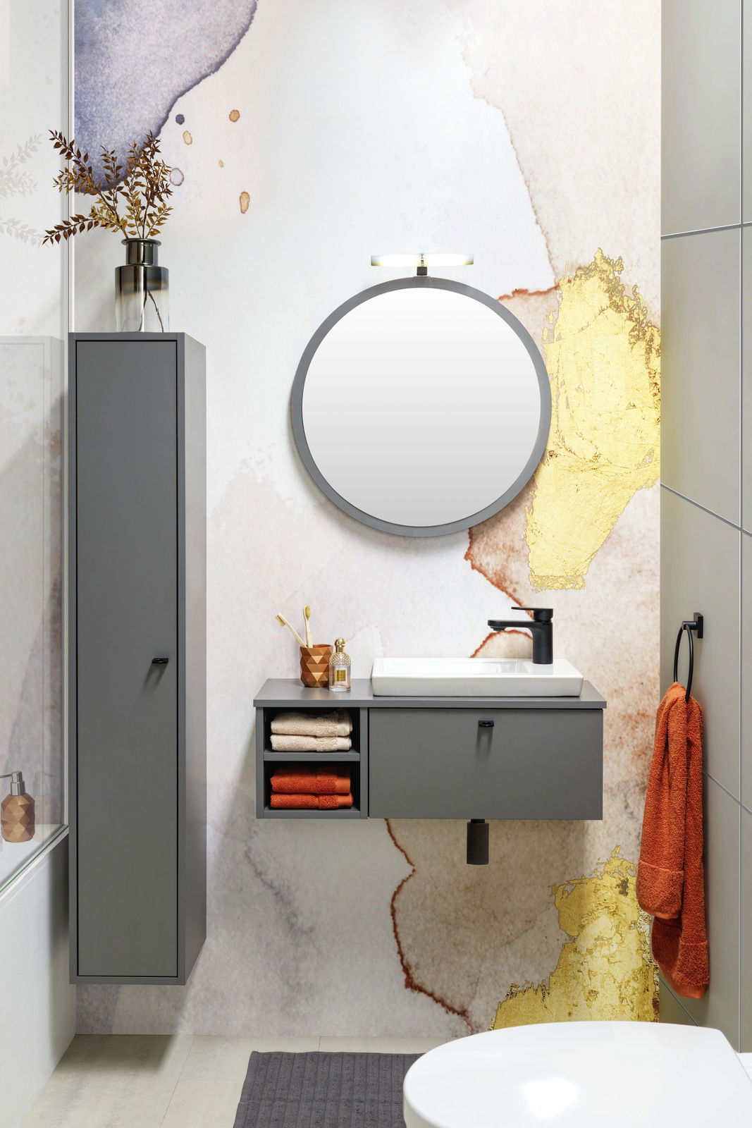 Modernes Waschtisch-Set in einem stilvollen Badezimmer mit grauen Schränken, rundem Spiegel und dekorativen Elementen, aus der Perspektive von vorne betrachtet.