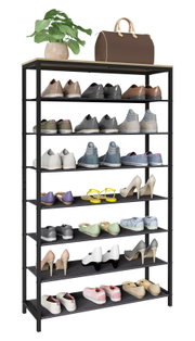 Schwarzes Schuhregal mit mehreren Ablagen und heller Deckplatte, bestückt mit verschiedenen Schuhpaaren; oben Pflanze im Topf und braune Reisetasche, Ansicht leicht von vorne links.