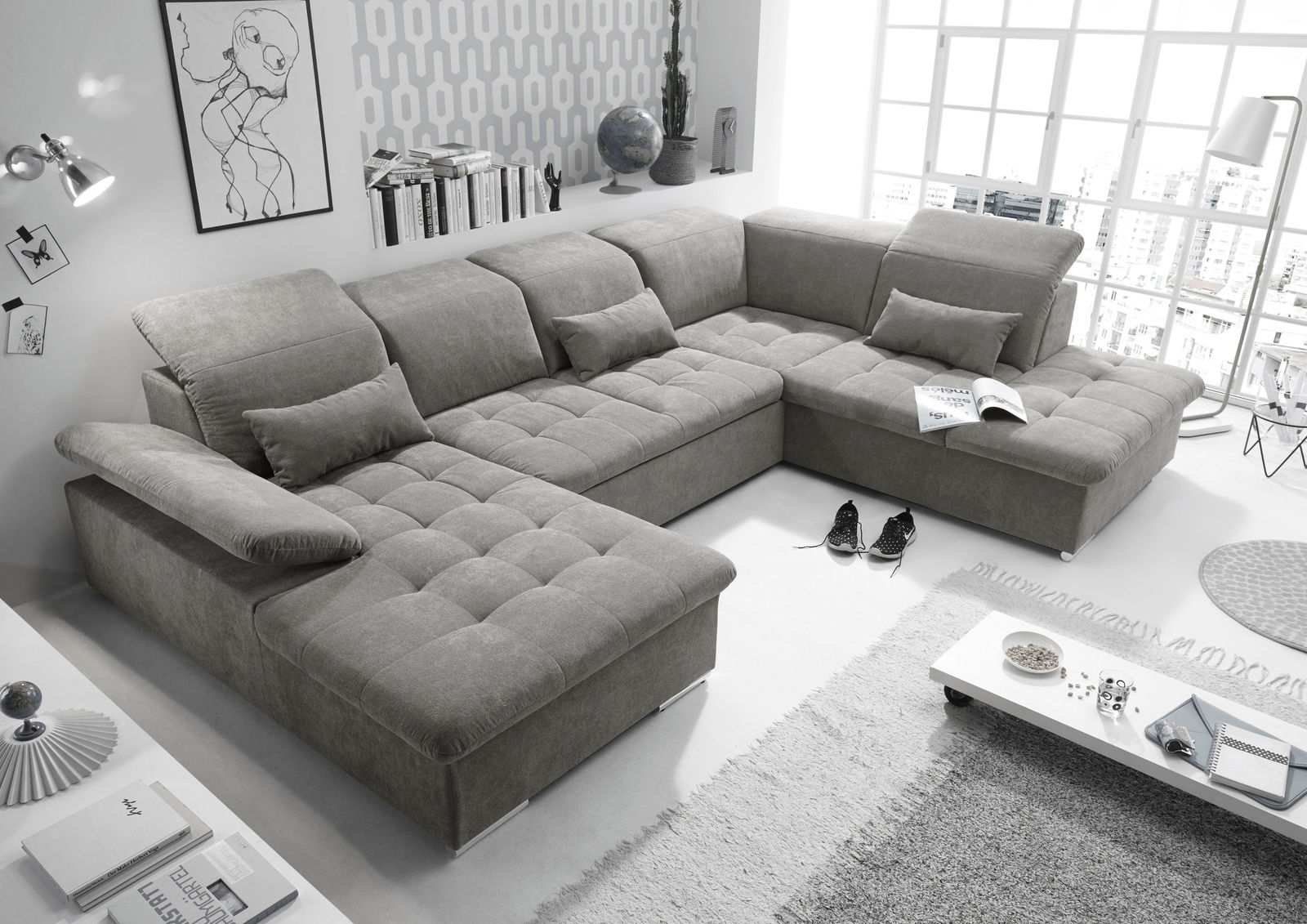 Graues, modernes Ecksofa in U-Form mit verstellbaren Kopfstützen und Kissen, in einem hellen Wohnzimmer mit großen Fenstern und stilvoller Dekoration. Perspektive von oben.