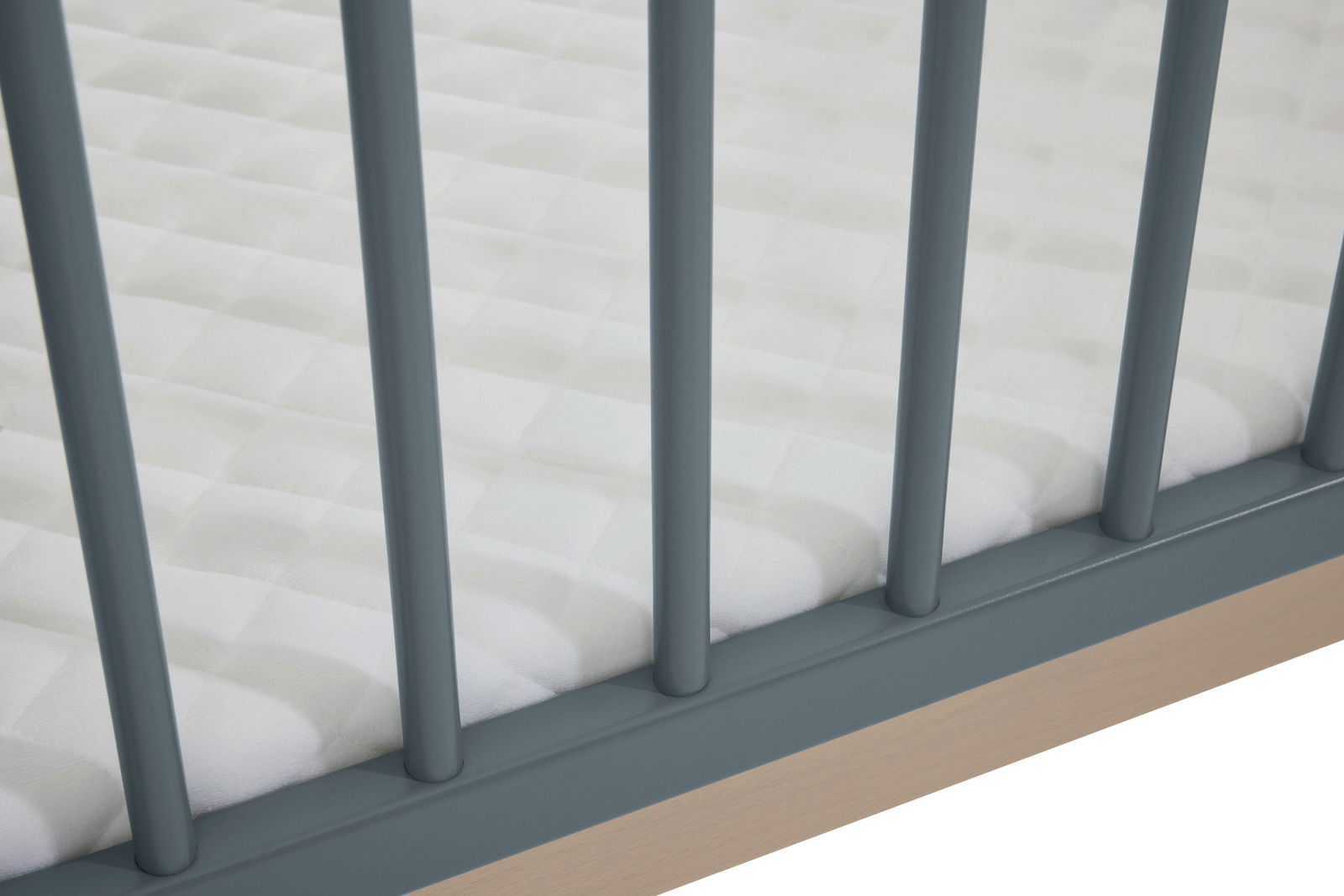 Nahaufnahme eines Anstellbetts mit blauen Gitterstäben und weißer Matratze, von oben betrachtet.
