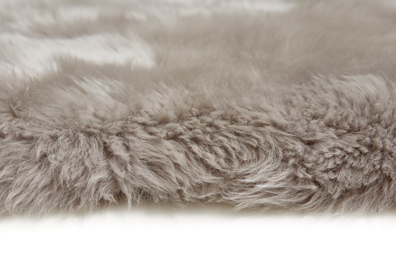Nahaufnahme eines grauen Schaffells, das eine weiche und flauschige Textur zeigt, seitliche Perspektive