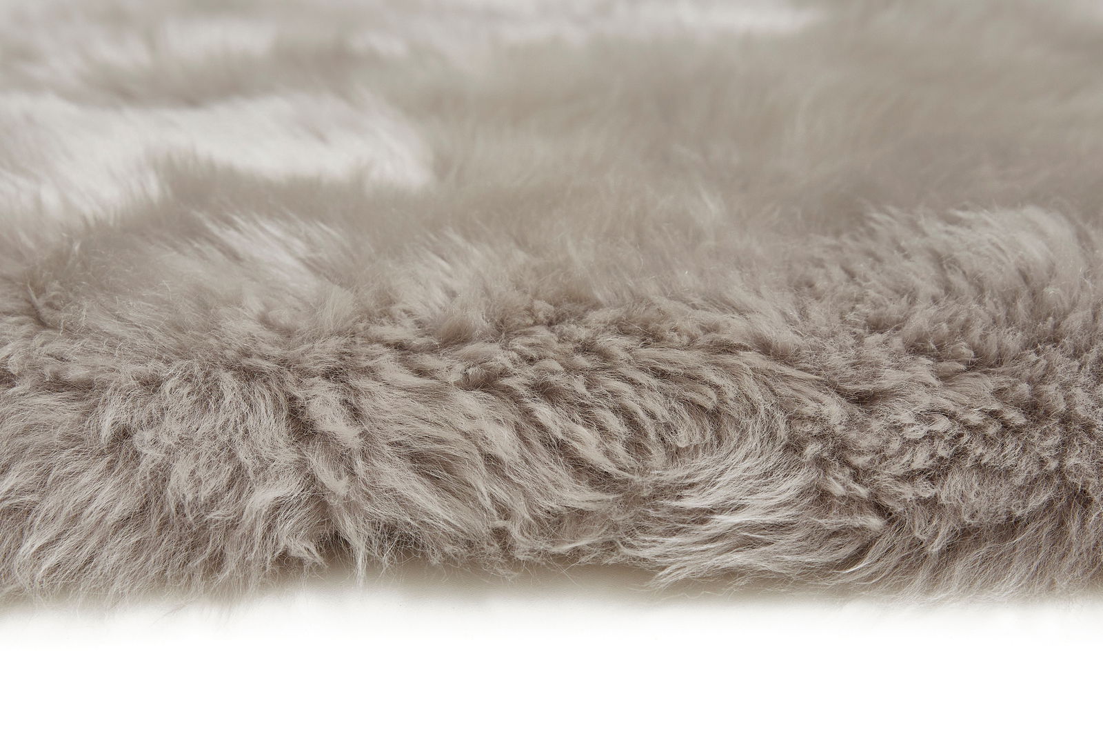 Nahaufnahme eines grauen Schaffells, das eine weiche und flauschige Textur zeigt, seitliche Perspektive