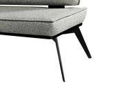 Nahaufnahme einer modernen Bank mit grauem Polster und schwarzen Metallbeinen, seitliche Perspektive