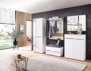 Moderne Garderobenset in einem hellen Raum mit großem Fenster, bestehend aus einem hohen Schrank, einem Garderobenpaneel mit Haken und Ablage, einer Sitzbank mit Stauraum und einem Spiegel. Perspektive von vorne.