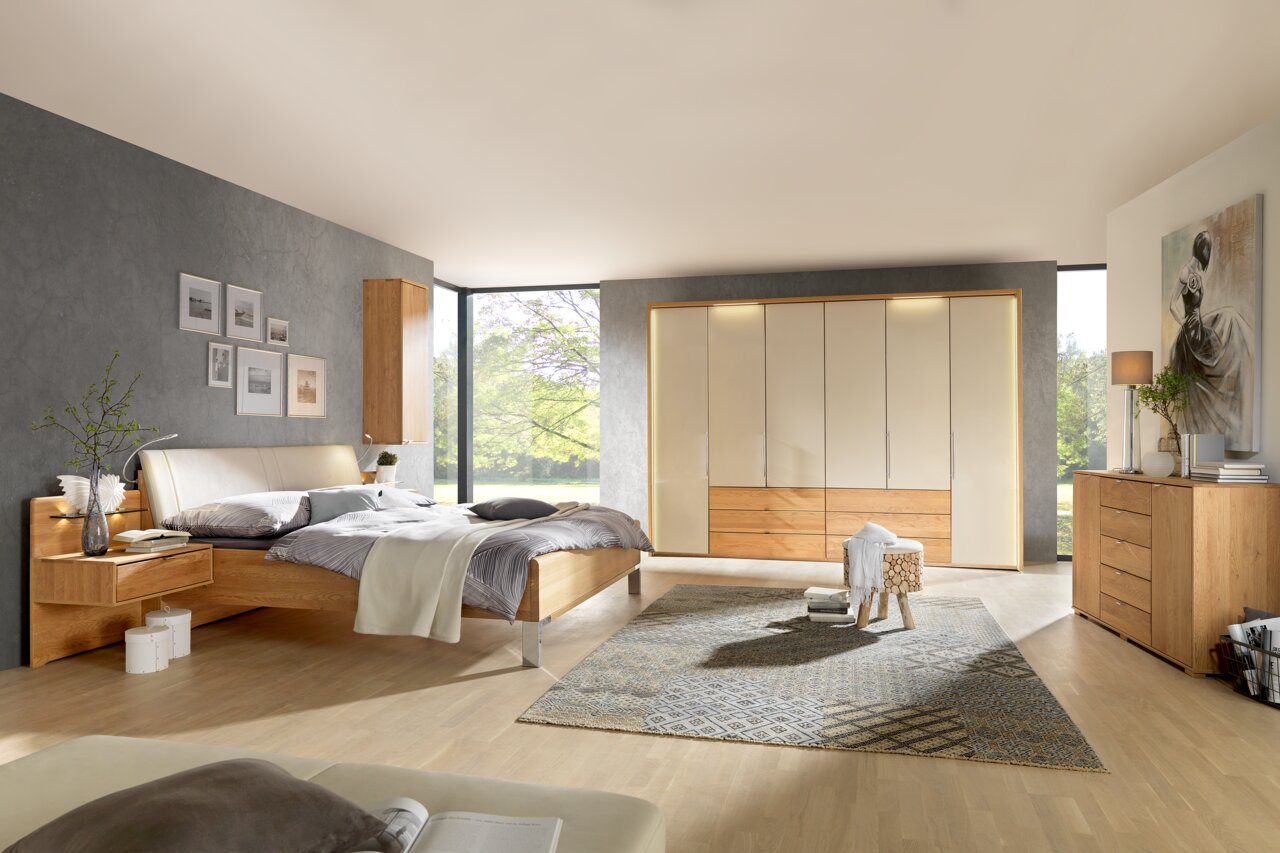 Moderner Schlafzimmerblick mit Dieter Knoll Gleittüren-Funktionsschrank AMATO in Holzoptik, umgeben von stilvollen Möbeln und natürlichem Licht.