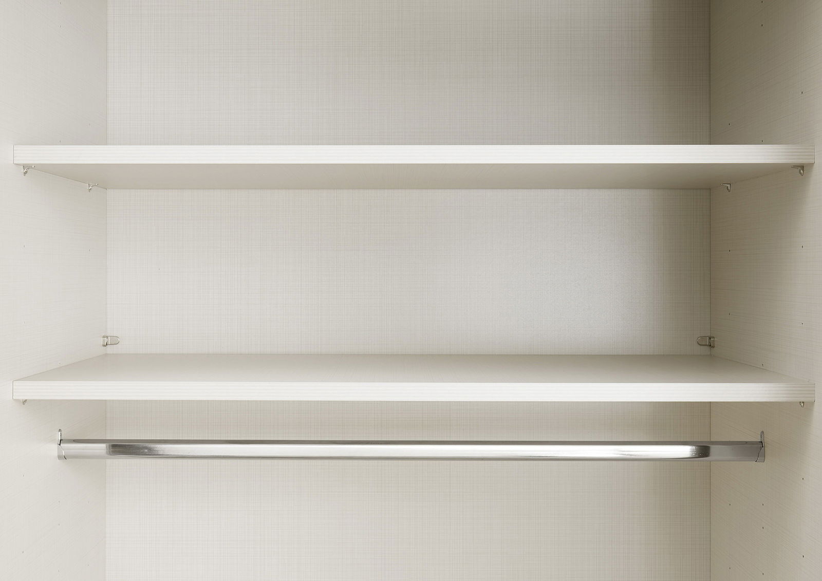 Innenansicht eines Schwebetürenschranks mit zwei Regalböden und einer Kleiderstange, frontal betrachtet.