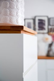 Nahaufnahme einer weißen Hochkommode mit Holzplatte, seitliche Perspektive