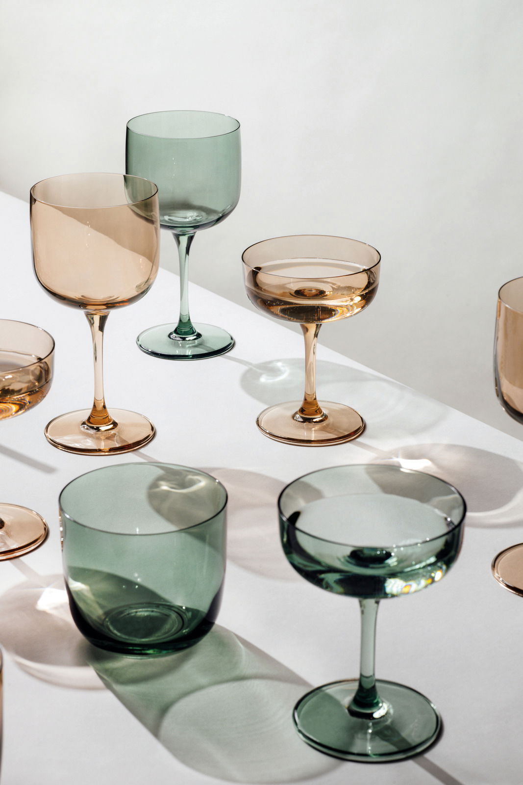 Verschiedene Longdrinkbecher in Grün- und Brauntönen auf einem weißen Tisch, aus der Vogelperspektive fotografiert.