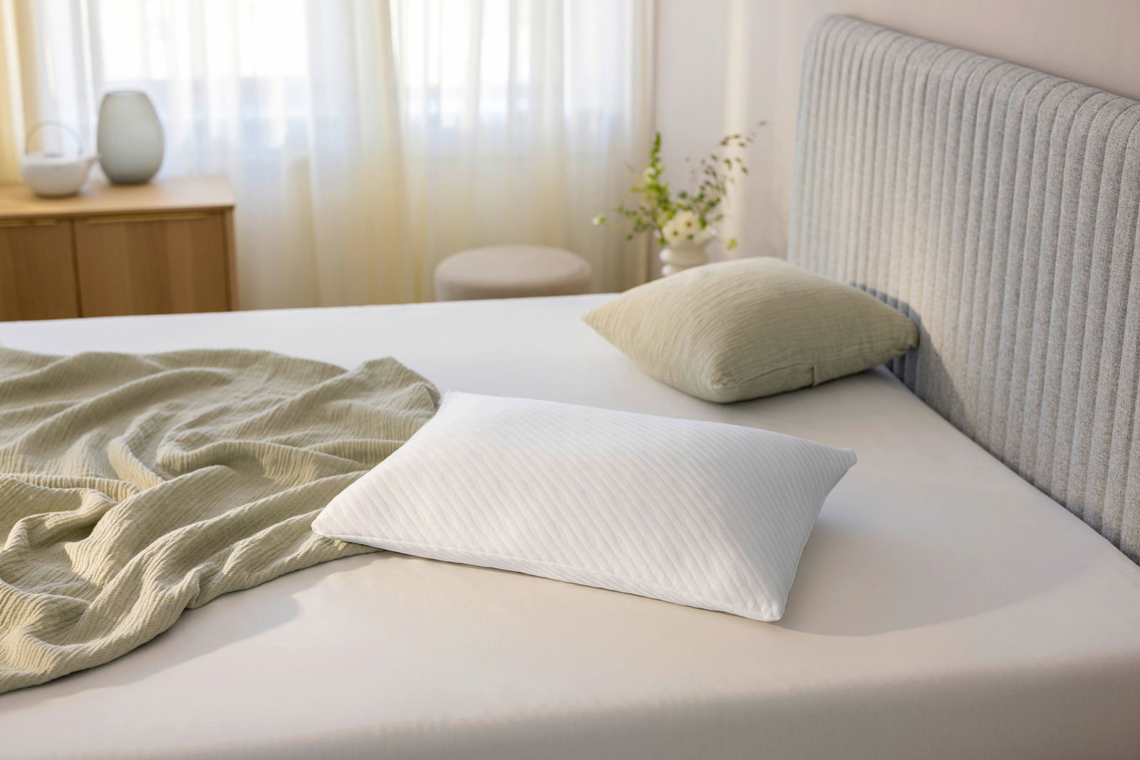 Tempur Schlafkissen 80 x 40 cm PRIMA Schlafkissen 80 x 40 cm auf einem Bett, seitliche Perspektive, mit einem grünen Kissen und einer Decke im Hintergrund.