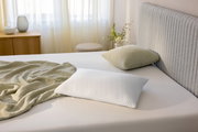Schlafkissen 80 x 40 cm auf einem Bett, seitliche Perspektive, mit einem grünen Kissen und einer Decke im Hintergrund.