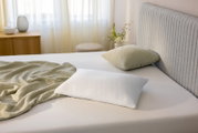 Schlafkissen 80 x 40 cm auf einem Bett, seitliche Perspektive, mit einem grünen Kissen und einer Decke im Hintergrund.