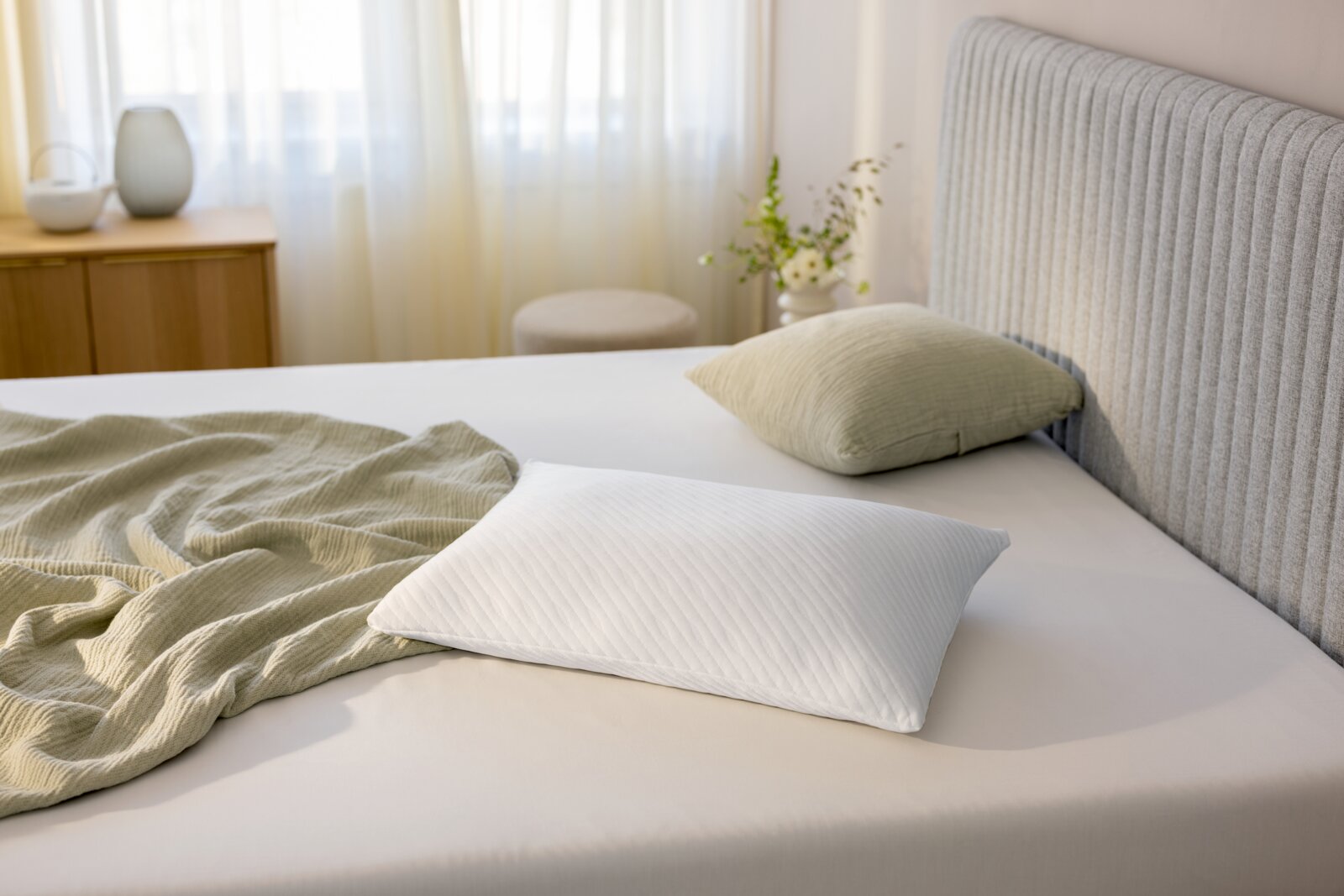 Schlafkissen 80 x 40 cm auf einem Bett, seitliche Perspektive, mit einem grünen Kissen und einer Decke im Hintergrund.