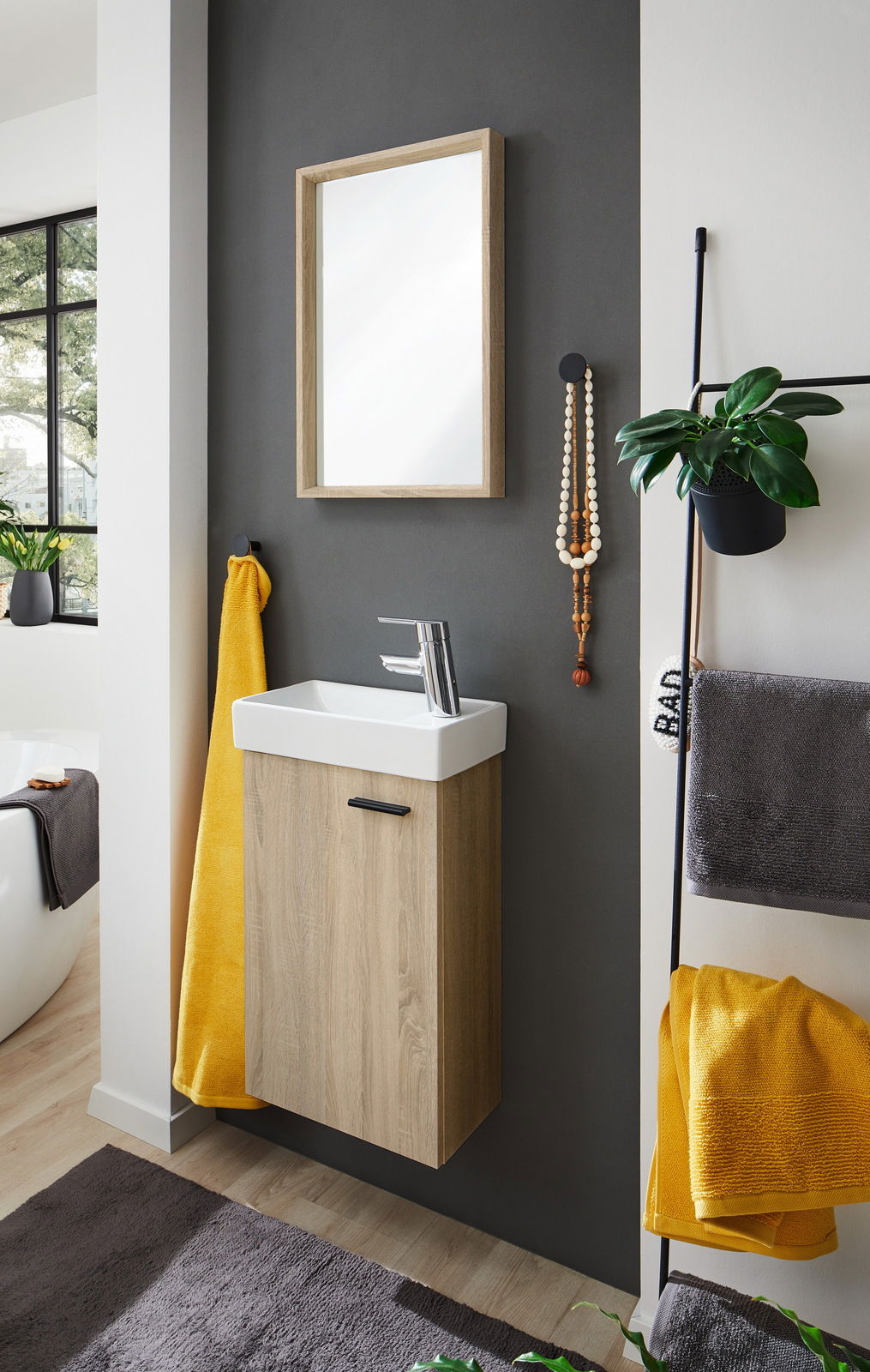 Modernes Gästebad mit hängendem Waschtisch aus Holzoptik, weißem Waschbecken und Spiegel, seitliche Perspektive.