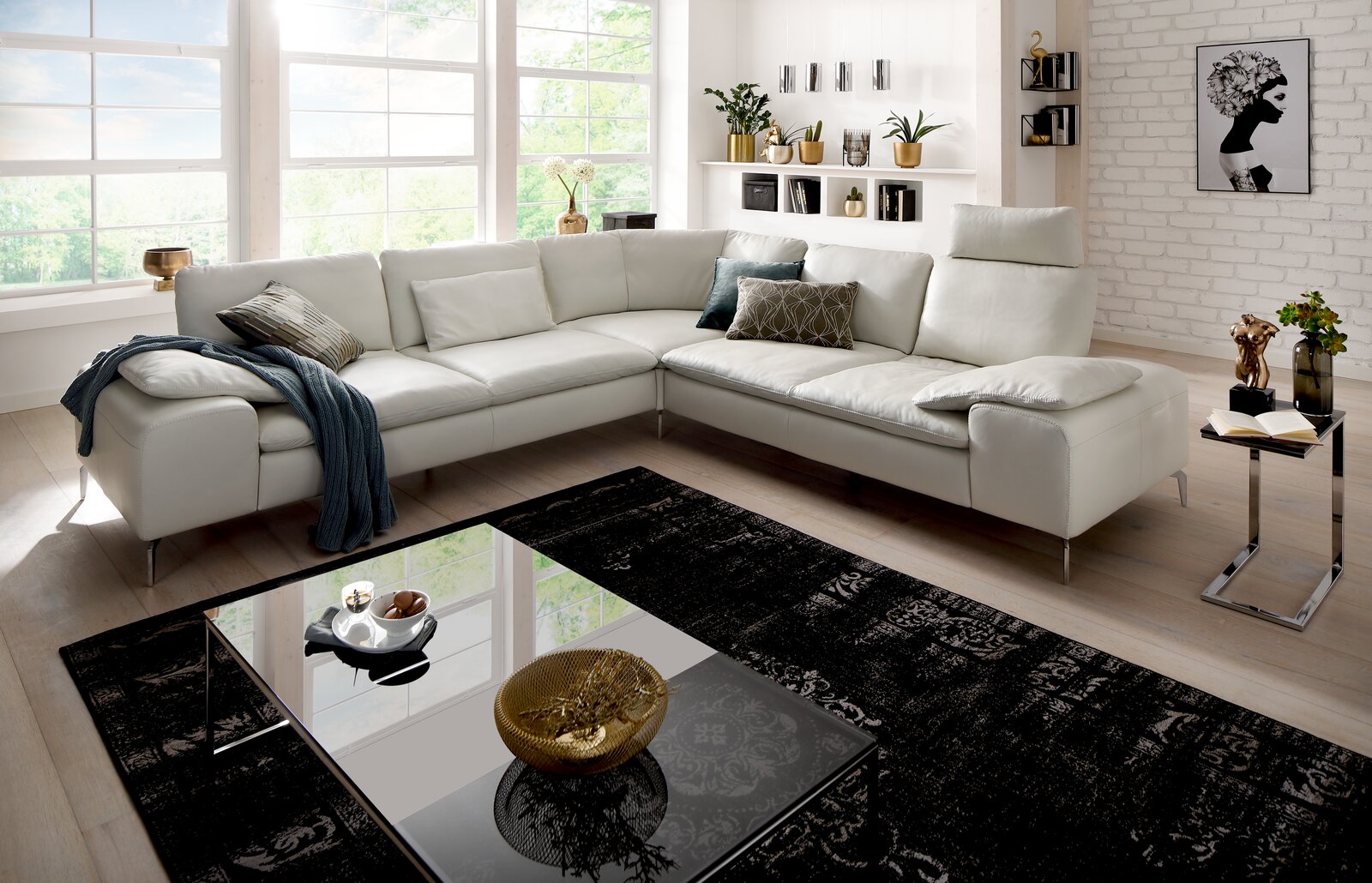 Moderne weiße Polsterrundecke in einem hellen Wohnzimmer mit großen Fenstern, dekoriert mit Kissen und einer Decke, aus der Perspektive von vorne links.