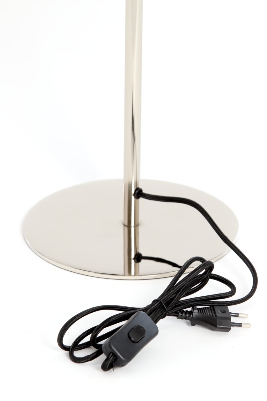 Nahaufnahme der Basis einer Tischleuchte mit glänzendem Metallfuß und schwarzem Kabel mit Schalter, seitliche Perspektive.