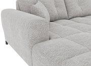 Detailaufnahme eines hellgrauen, strukturiert bezogenen Sofas mit gepolsterter Armlehne, gesteppter Sitzfläche und Rückenkissen, schräg von vorne links fotografiert.