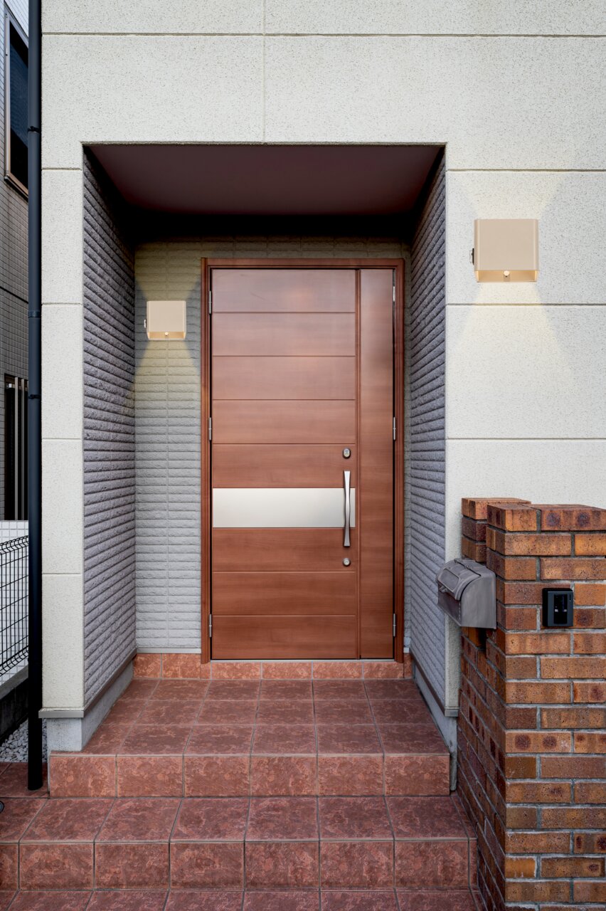 Moderne Akku-Wandleuchte neben einer Eingangstür, frontal betrachtet