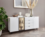 Modernes weißes Sideboard mit Schubladen und Glastür, dekoriert mit Büchern, Vase und Pflanzen, seitliche Perspektive.