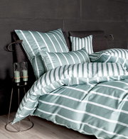 Bettwäsche-Set in grün-weißem Streifenmuster auf einem Bett mit dunklem Kopfteil, seitliche Perspektive