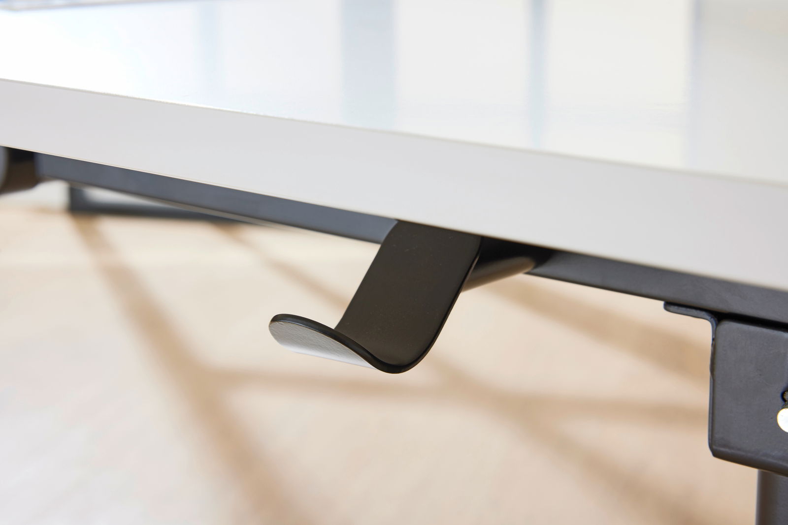 Nahaufnahme eines Schreibtischhakens unter einer weißen Tischplatte, seitliche Perspektive
