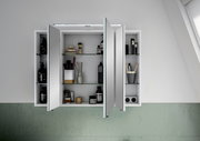 Spiegelschrank mit geöffneten Türen, gefüllt mit Pflegeprodukten und Accessoires, aus frontaler Perspektive.