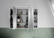 Spiegelschrank mit geöffneten Türen, gefüllt mit Pflegeprodukten und Accessoires, aus frontaler Perspektive.