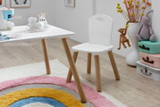 Weißer Kinderstuhl mit Holzbeinen neben passendem weißem Tisch im Kinderzimmer, seitliche Perspektive auf Sitzfläche und Rückenlehne