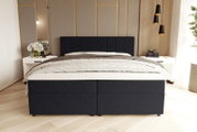 Dunkelblaues, gepolstertes Boxspringbett mit quadratisch gestepptem Kopfteil und weißer Bettwäsche in modernem Schlafzimmer, frontale Ansicht auf Augenhöhe.