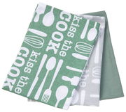 Dreiteiliges Geschirrtuch-Set 'Kiss The Cook' in Grün und Grau mit Küchenutensilien-Motiven, aus der Vogelperspektive.