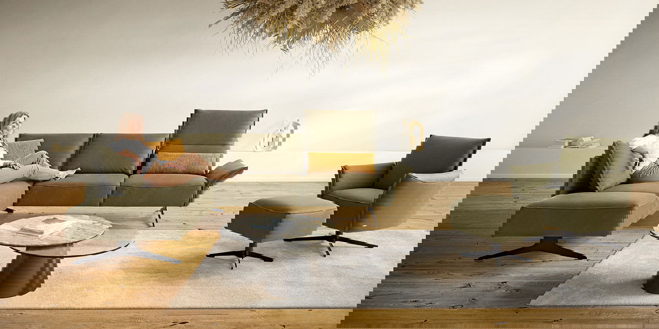 Modernes helles Wohnzimmer mit einem grünen Ecksofa und passendem Sessel mit Fußhocker.